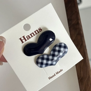 Detail of heart-shaped hair clips in black and checkerboard patterns on a card