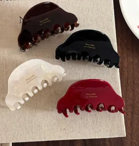 Close-up of set of four acetate hair claws in assorted colors with gold lettering