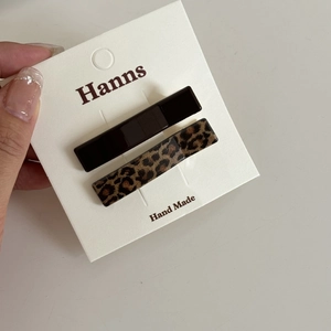 Detailed view of leopard print and dark brown hair clips on a handmade display card