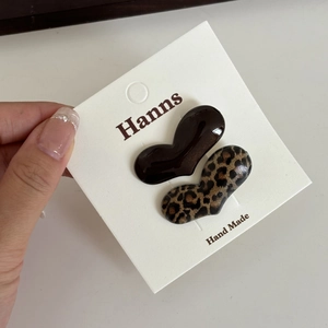 Detail shot of heart-shaped leopard print and brown resin hair clips on display card