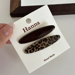 Close-up of leopard print and dark brown resin hair clips on a branded display card