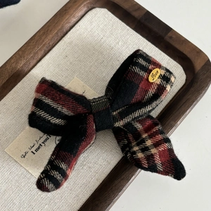 Classic British plaid bow hair clip with Love gold metal accent on linen background