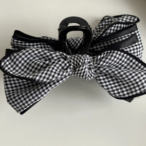 Close-up of a large black and white plaid bow hair claw clip with layered ribbon detail