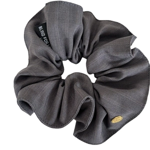 Elegant dark grey striped fabric scrunchie with gold charm and woven label detail