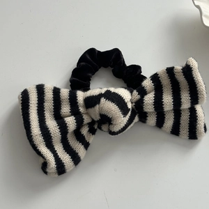 Close-up of a black and white striped knitted bow scrunchie with velvet band