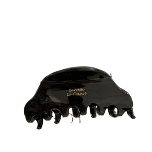 Glossy black acetate shark hair clip with gold logo detail for an elegant French look