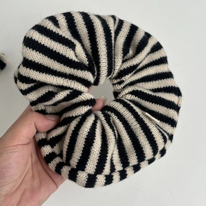 Close-up of black and white striped knitted hair scrunchie with soft ribbed texture