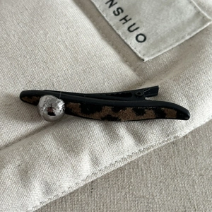 Brown leopard print flocking bow hair clip with silver bead accent on canvas background