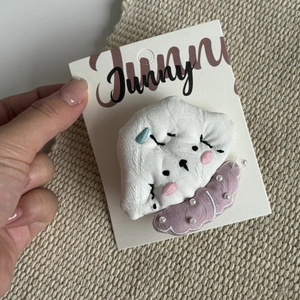Cute embroidered cloud hair clip with pink wavy base and pearl detail on a card