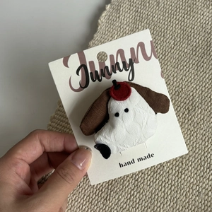 Detail showing a handmade plush puppy hair clip on brand packaging for girls