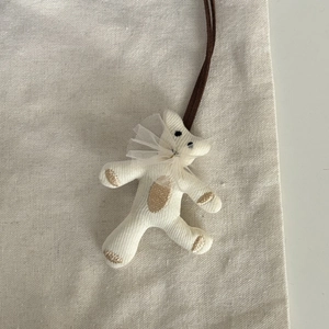 Détail d'un pendentif ours en tricot fait main avec col en dentelle et broderie brune