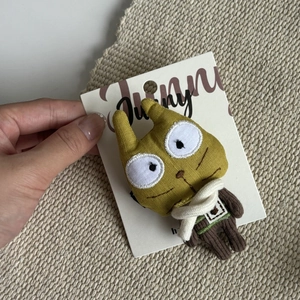 Close-up of cute yellow plush animal clip with striped knit vest and white scarf