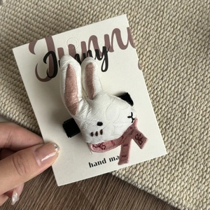 Close-up of handmade plush bunny hair clip with pink scarf on display card