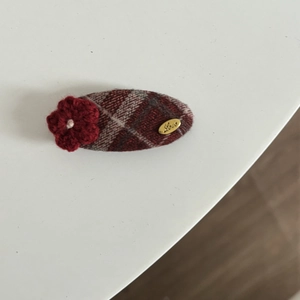 Close-up of vintage red plaid fabric hair clip with a crochet flower and gold Love tag