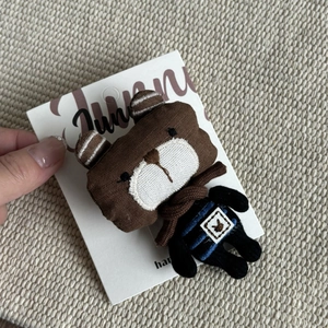 Close-up of a brown stuffed cartoon bear hair clip on a white paper display card