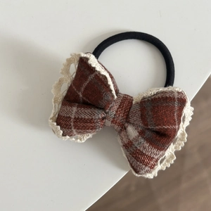 Detail of red checkered bow hair tie with delicate white lace trim on elastic band