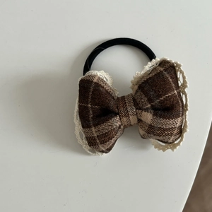 Detail of red and brown plaid bow hair tie with cream lace trim on a white background