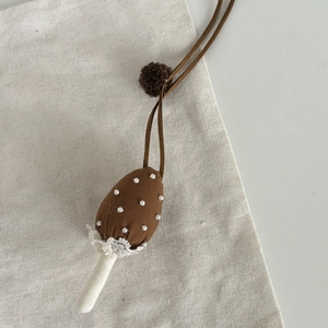 Gros plan du pendentif champignon en lin fait main avec dentelle et détails de perles