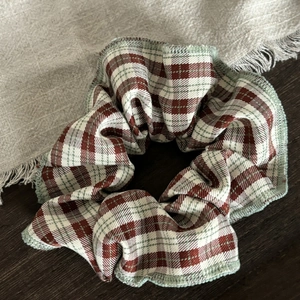 Green and white plaid fabric hair scrunchie with mint green stitching on wooden background