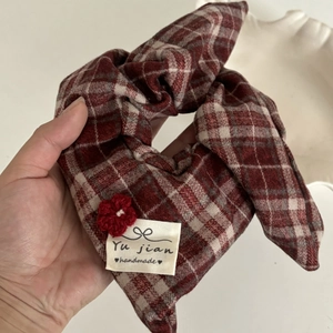 Close-up of red and white plaid hair scrunchie with handmade crochet flower detail