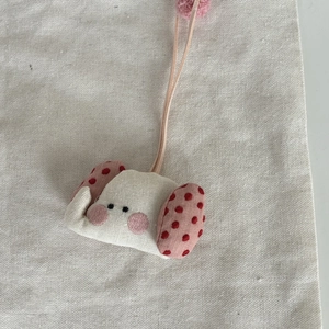 Détail d'un pendentif artisanal en coton avec oreilles à pois roses et pompon doux
