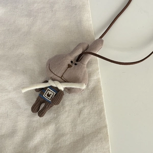 Détail d'un pendentif lapin en tricot marron fait main avec texture fine et cordon en cuir