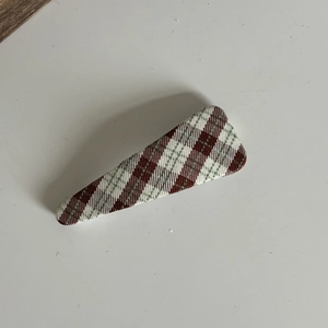 Detail of vintage green plaid fabric bow hair clip with textured weave and red accents