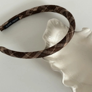 Brown checkered fabric headband with handmade tag on white ceramic tray background