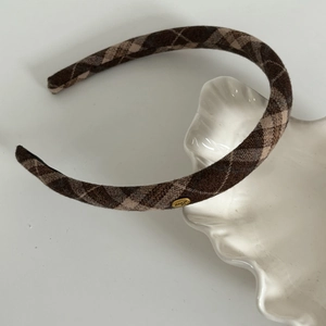 Detailed view of brown plaid headband featuring gold Love metal plaque and soft fabric texture