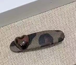 Gros plan d'une pince à cheveux léopard avec détail coeur brun sur texture tissée