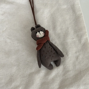 Détail d'un pendentif ours en lin marron fait main avec écharpe rouge et broderie