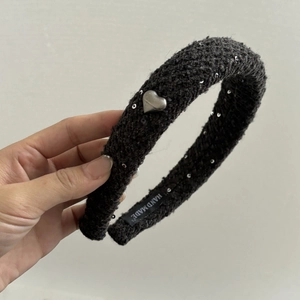 Détail d'un serre-tête en tissu pailleté sombre avec breloque cœur et étiquette fait main