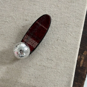 Gros plan détaillé d'une barrette en tissu à carreaux rouge et noir avec perle argentée