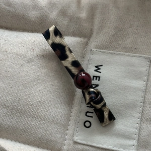 Macro shot of leopard print leather hair clip with a red bead and bow knot detail