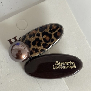 Detail of leopard print and dark brown oval hair clips with gold lettering on card