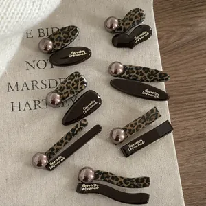 French leopard print hair clip set with brown resin and pearl accents on wooden background