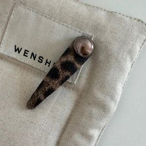 Vintage leopard print hair clip with brown resin bead on stylish fabric background