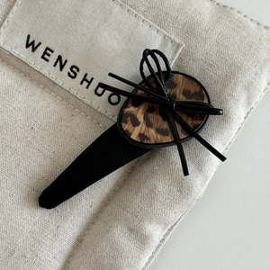 Detail of leopard print hair clip with black bow and acrylic finish on canvas