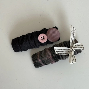 Close-up of pink plaid bow hair clip and black pleated fabric clip with vintage buttons
