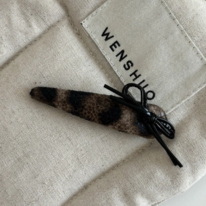 Detailed view of leopard print hair clip with black bow and soft plush velvet texture