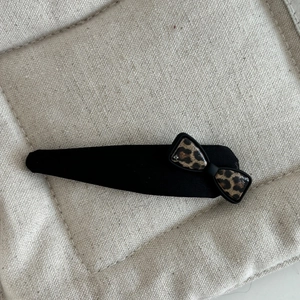Detail of fabric hair clip with leopard print bow and knot on textured background