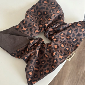 Detail of a large leopard print hair scrunchie with soft fabric pleats and woven tag
