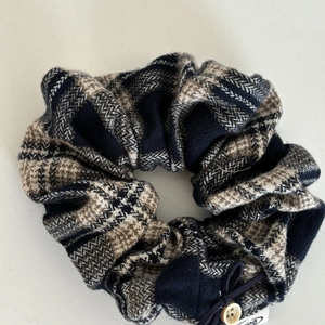 Detail of plaid scrunchie with wooden button and bow tie on white background