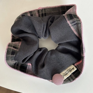 Detail of pink and blue plaid scrunchie with a fabric button and brand label