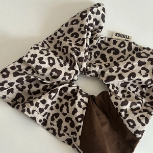 Detail of a large leopard print and brown fabric scrunchie with white brand tag