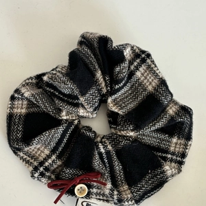 Close-up of checkered fabric hair scrunchie with red bow and vintage button detail