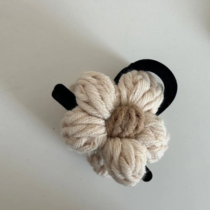 Détail en gros plan d'une pince à cheveux fleur en laine tricotée avec des pétales crème