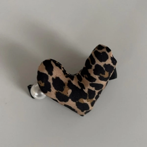 Detailed view of plush heart-shaped leopard print hair clip with a small white pearl