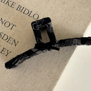 Detail of large claw clip covered in black and white checkered fabric on a rustic page