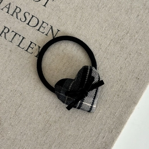 Detail of plaid heart hair tie with velvet bow on rustic linen background texture